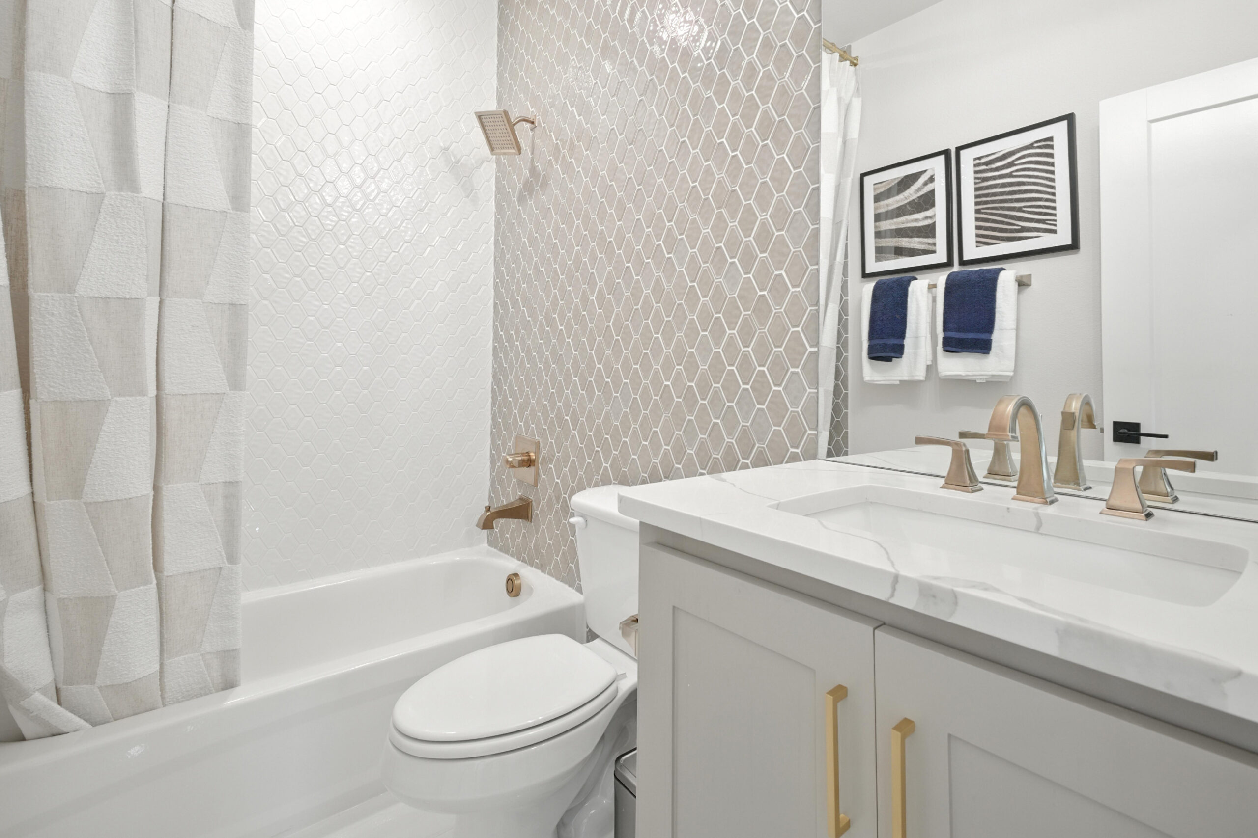Modern bathroom with clean white tile, fresh caulk lines, and brushed gold fixtures